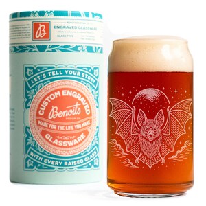 May include: A custom engraved beer glass with a bat design, filled with beer, next to a matching teal and orange container. The glass features a detailed bat illustration with a full moon and clouds. The container reads "Custom Engraved Glassware".