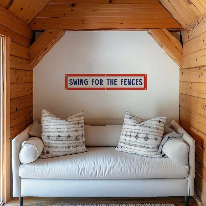 a cozy living room with a white couch and a wooden wall with a sign that says "Swing for the Fences".