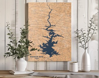 May include: Wooden wall art featuring a detailed map of Broken Bow Lake in navy blue against a light brown background. The lake's outline is prominent, with intricate river details. The text "BROKEN BOW LAKE" is displayed at the bottom. The art is displayed on a wooden table with white vases.