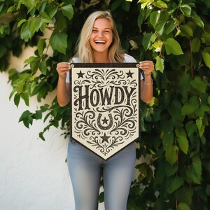 A smiling woman holding a banner with the word "HOWDY" on it.