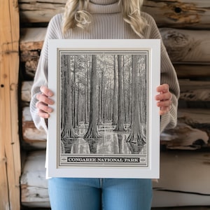 May include: A black and white illustration of tall trees in a swamp. The image is framed in a white frame with the text "Congaree National Park" at the bottom.