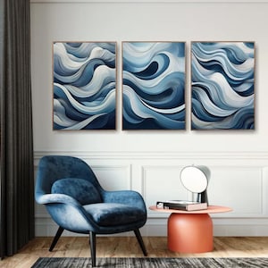 Puede incluir: Tres impresiones de arte abstracto con un diseño de olas azules y blancas. Las impresiones están enmarcadas en un marco fino marrón y están colgadas en una pared blanca.