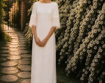 May include: A floor-length white dress featuring a boat neckline, three-quarter length sleeves with wide lace trim, and a matching lace border at the hem. The garment is made of a smooth, solid fabric and is paired with white pointed-toe heels.