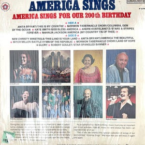 Op de afbeelding: Een achterkant van een vinylplaat met de titel America Sings For Our 200th Birthday. Het bevat een tracklist voor kant A en kant B, samen met acht fotografische portretten van artiesten zoals Anita Bryant en Robert Goulet, plus tekst.