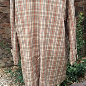 May include: A plaid shirt with a tan collar. The shirt is on a white mannequin and has a light brown, orange, and white plaid pattern.