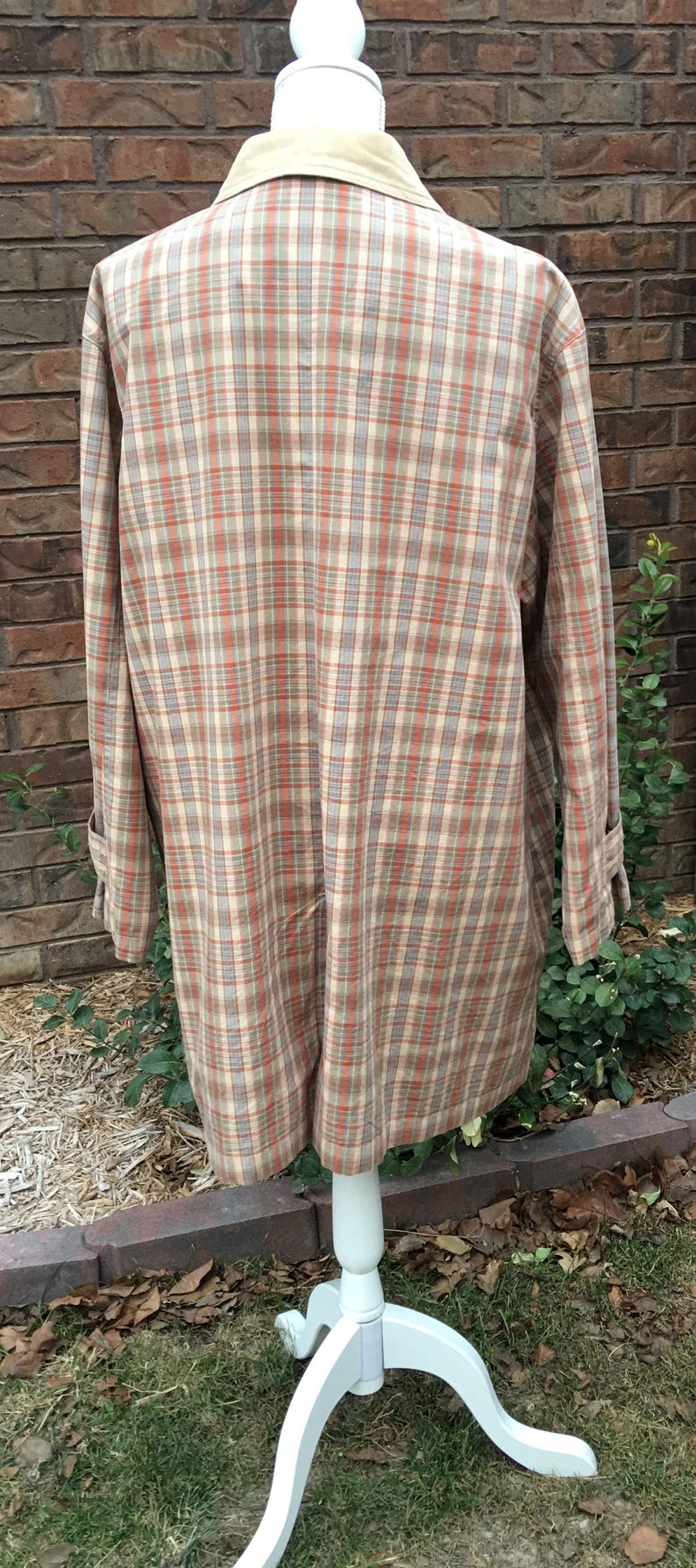 May include: A plaid shirt with a tan collar. The shirt is on a white mannequin and has a light brown, orange, and white plaid pattern.