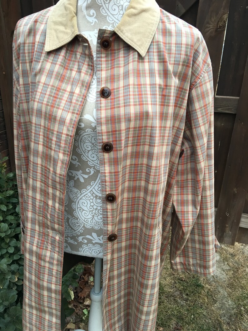 May include: A long, beige and orange plaid jacket with a corduroy collar. The jacket has a button-up front and long sleeves.