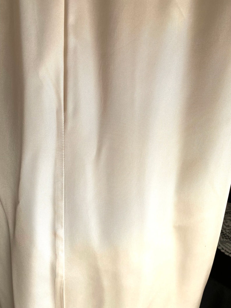 K&ouml;nnte beinhalten: Nahaufnahme eines wei&szlig;en Stoffes mit einer subtilen Textur. Der Stoff hat einen leichten Glanz und wirkt glatt und weich.