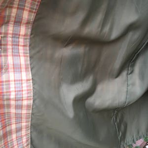 May include: The inside of a plaid jacket with a green lining. The lining is smooth and has a slight sheen.