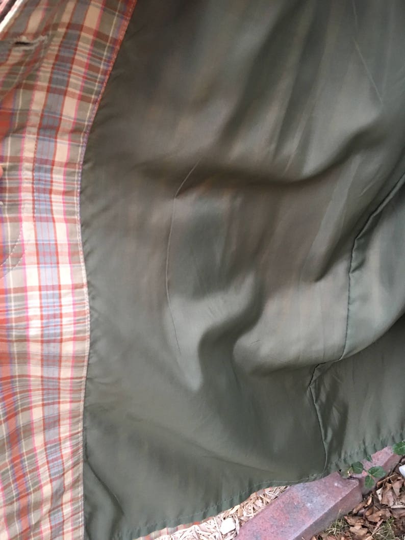 May include: The inside of a plaid jacket with a green lining. The lining is smooth and has a slight sheen.
