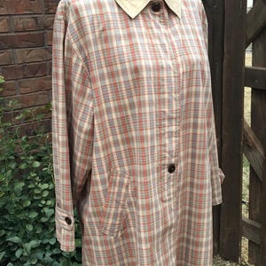 May include: A plaid shirt jacket with a corduroy collar. The jacket is on a white mannequin and has a light brown, beige, and red plaid pattern.