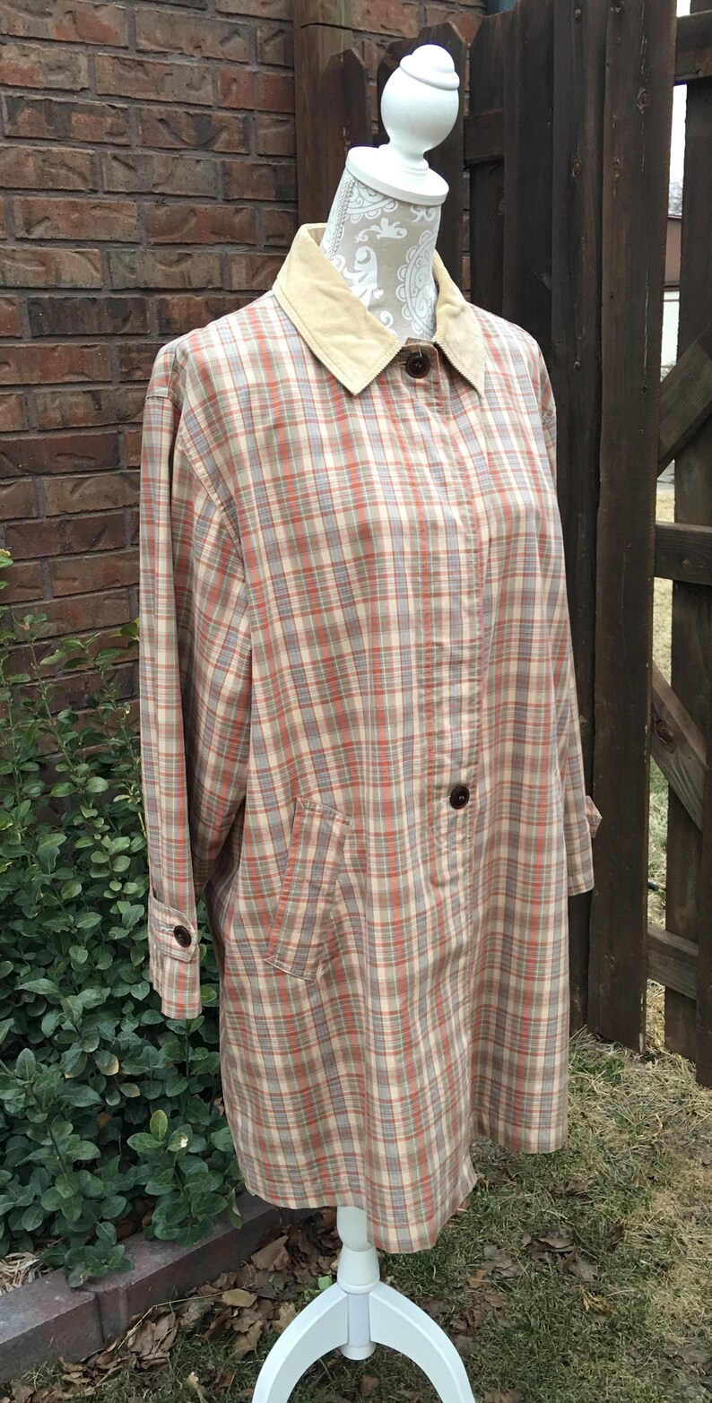 May include: A plaid shirt jacket with a corduroy collar. The jacket is on a white mannequin and has a light brown, beige, and red plaid pattern.