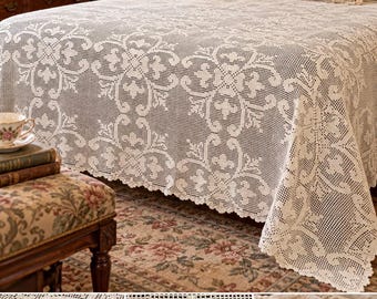 May include: An off-white crochet bedspread featuring an intricate, repeating floral and scrollwork pattern with a scalloped edge. The fabric has a grid-like openwork structure, showcasing detailed needlework that drapes over the sides of a bed.
