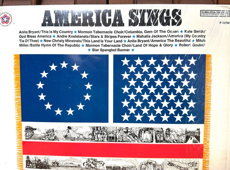 Op de afbeelding: Een vinylplatenhoes met de titel America Sings met een tracklist van patriottische liedjes. Het ontwerp bevat twee blauwe rechthoeken met witte sterren, een horizontale rode streep en zwart-wit historische illustraties met gele franje.