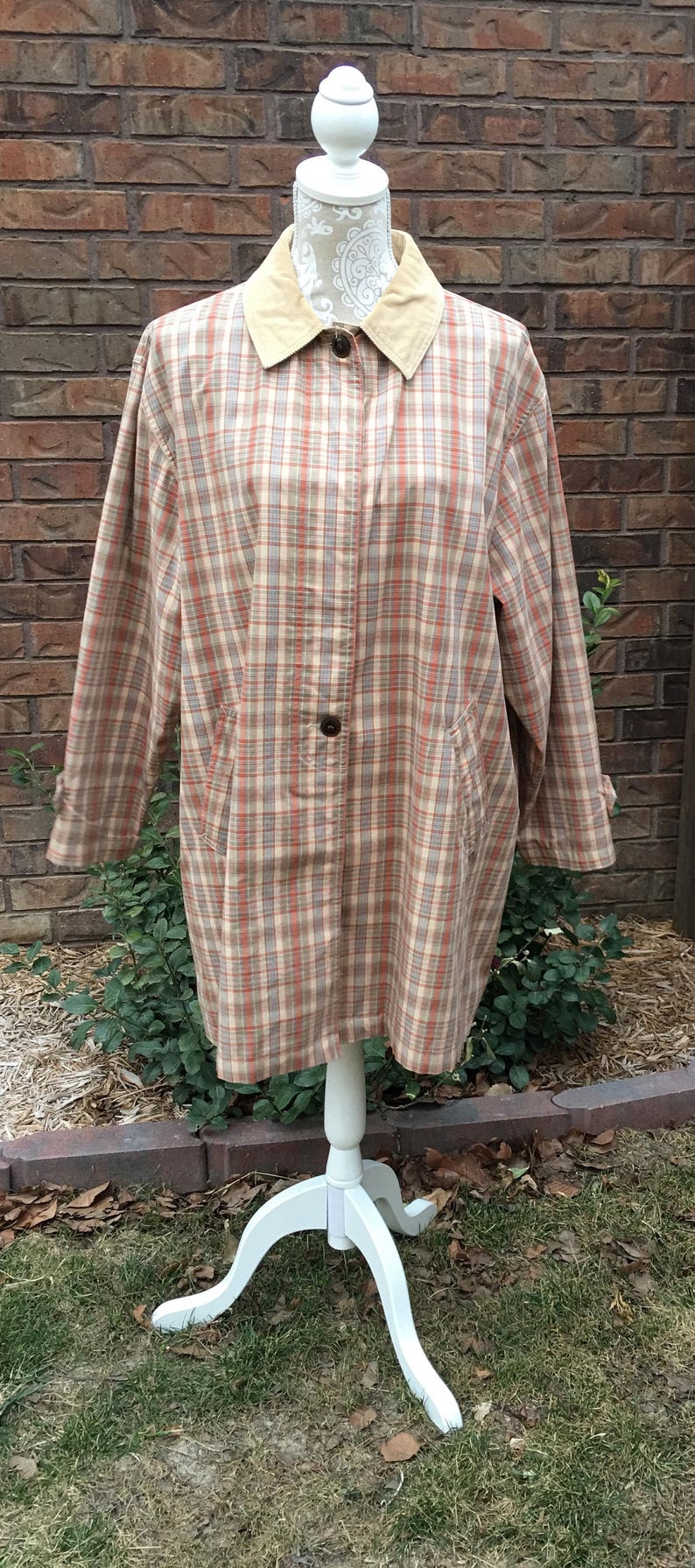 May include: A plaid shirt jacket with a tan corduroy collar. The jacket is on a white mannequin and has a button closure.