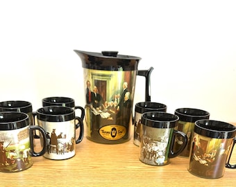 May include: A vintage pitcher and mug set with black rims and handles. The pitcher and mugs feature historical artwork. The set includes a pitcher with a black lid and handle, and eight matching mugs. The mugs and pitcher have a gold and black color scheme.