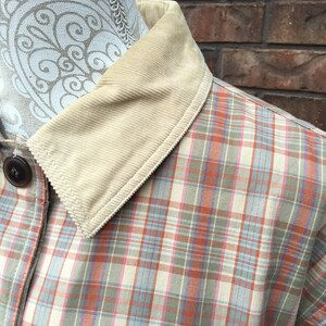 May include: A plaid shirt with a corduroy collar. The shirt is a light beige color with pink, blue, and orange plaid.