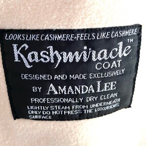 K&ouml;nnte beinhalten: Ein schwarzes und wei&szlig;es Etikett mit dem Text "LOOKS LIKE CASHMERE FEELS LIKE CASHMERE" und "Kashmiracle COAT" in einer stilisierten Schriftart. Das Etikett enth&auml;lt auch den Text "DESIGNED AND MADE EXCLUSIVELY BY AMANDA LEE" und "PROFESSIONALLY DRY CLEAN LIGHTLY STEAM FROM UNDERNEATH ONLY DO NOT PRESS THE LUXURIOUS SURFACE".