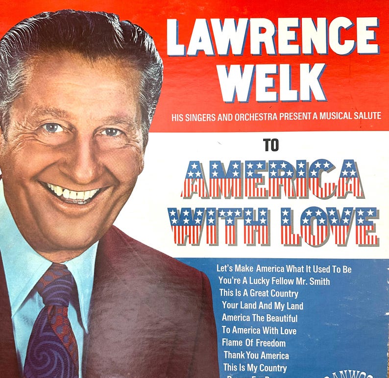 Op de afbeelding: Een vintage vinyl platenhoes met een portret van Lawrence Welk aan de linkerkant. De tekst luidt LAWRENCE WELK HIS SINGERS AND ORCHESTRA PRESENT A MUSICAL SALUTE TO AMERICA WITH LOVE, gevolgd door een tracklist inclusief America The Beautiful.