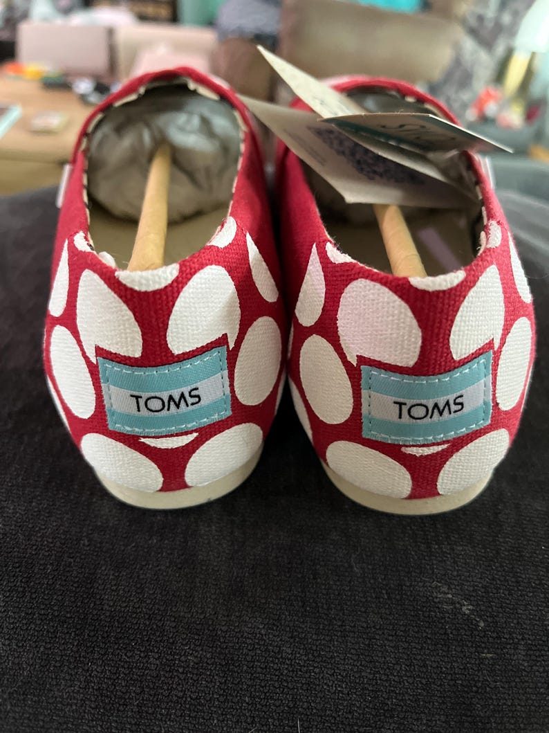May include: A pair of red and white polka dot canvas shoes with the word "TOMS" on the side of each shoe.