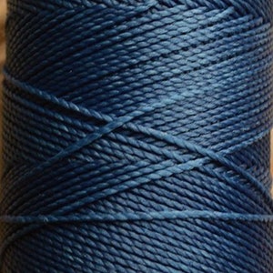 May include: A spool of dark blue waxed linen thread.
