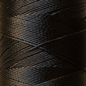 May include: A spool of black waxed thread. The thread is wound tightly on the spool and has a smooth, shiny finish.