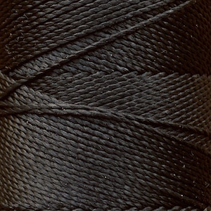 May include: A spool of black waxed cord. The cord is tightly wound and has a smooth, polished finish.