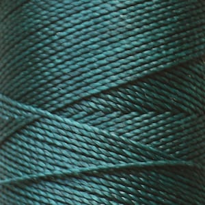 May include: A spool of dark green twine, wound tightly and ready for use in crafting or other projects.