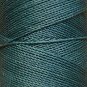 May include: A spool of teal blue waxed cotton cord.