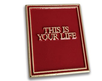 以下が含まれることがあります： 赤い背景に金色の文字で「This is Your Life」と書かれた金色のエナメルピン