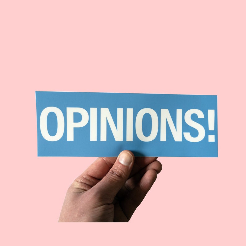 May include: A hand holds up a blue sign with the word "OPINIONS!" printed in white.