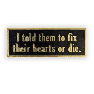 gold pin with "I told them to fix their hearts or die"
