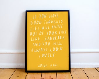May include: A yellow framed print with a white quote by Roald Dahl that reads: "If you have good thoughts they will shine out of your face like sunbeams and you will always look lovely."