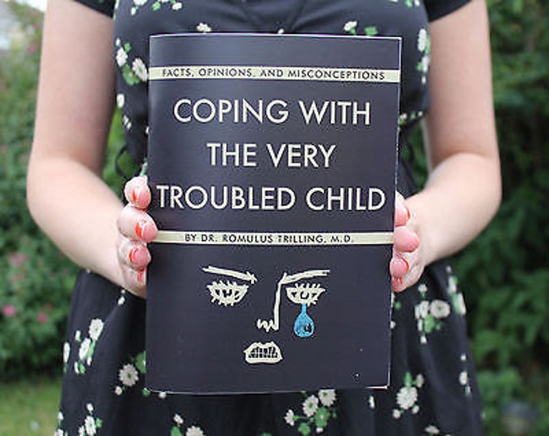 Pu&ograve; includere: Un libro nero con il titolo "Coping with the Very Troubled Child" di Dr. Romulus Trilling, M.D. La copertina presenta un'illustrazione in bianco e nero di un viso che piange.
