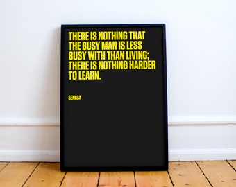 May include: A black and white framed print with a yellow quote by Seneca: "There is nothing that the busy man is less busy with than living; there is nothing harder to learn."