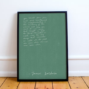 Puede incluir: Una impresión enmarcada con fondo verde y texto blanco. El texto es una cita de James Baldwin: "Piensas que tu dolor y tu angustia son sin precedentes en la historia del mundo, pero este no es el momento para sentir eso. No fueron las cosas en sí mismas las que me enseñaron tanto como las cosas conectadas que todas las personas que estaban vivas habían estado vivas."