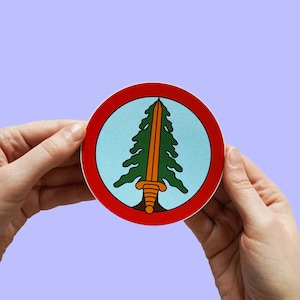 May include: A red circle sticker with a blue background and a green pine tree with a sword through it. The sword is orange and has a gold handle.
