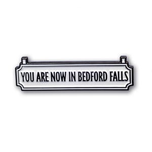 Puede incluir: Pin de esmalte blanco con letras negras que dice "You are now in Bedford Falls". El pin tiene forma de señal de calle con bordes negros.