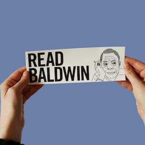 Könnte beinhalten: Ein weißes Schild mit schwarzem Text, auf dem "Read Baldwin" steht. Im unteren rechten Eck des Schildes befindet sich eine Schwarzweißillustration einer Person.