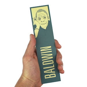 Puede incluir: Un marcapáginas azul verdoso con el nombre "BALDWIN" impreso en letras amarillas. Un dibujo lineal de un rostro masculino se encuentra en la parte superior del marcapáginas.