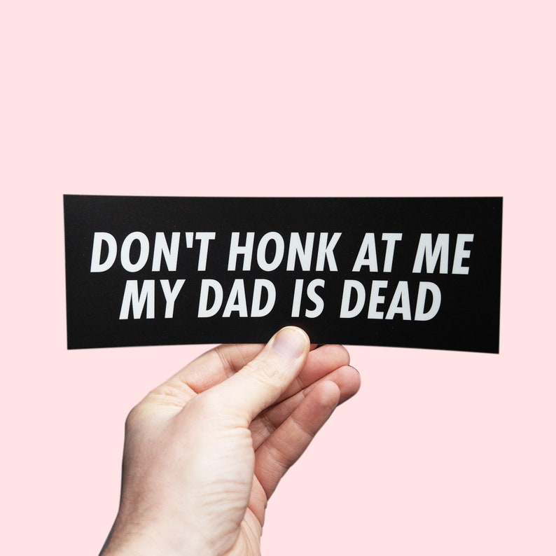 May include: A black and white bumper sticker with the text "DON'T HONK AT ME MY DAD IS DEAD".