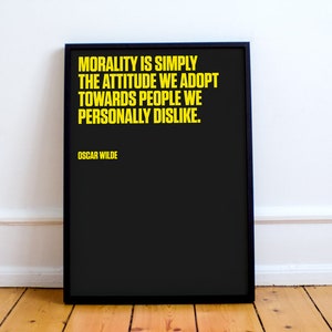 May include: Black and white framed print with a yellow quote by Oscar Wilde: "Morality is simply the attitude we adopt towards people we personally dislike."