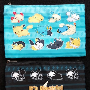 May include: Two zippered pouches. The top pouch is light blue with cartoon characters and lightning bolt designs. The bottom pouch is black with white skeleton cartoon characters and the text "It's Electric!"
