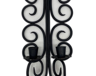 May include: Black metal wall-mounted candle holder with a decorative scroll design and two candle cups.