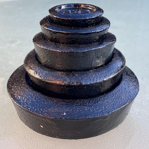 May include: A set of six black cast iron weights stacked in a pyramid shape. The weights are smooth and have a glossy finish.