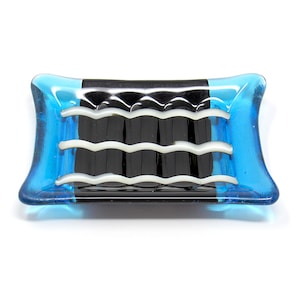 May include: A blue and black glass soap dish with a wavy white design. The dish is rectangular with rounded edges.