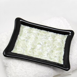 May include: A rectangular soap dish made of glass with a black rim and a white and green marbled design.