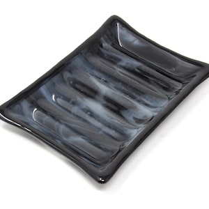 May include: A black glass soap dish with a rippled design and white streaks throughout.