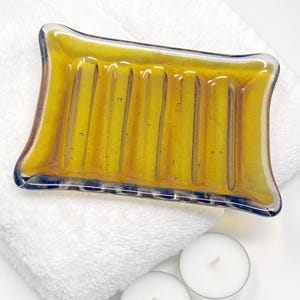 May include: A amber glass soap dish with a ridged design. The dish is sitting on a white towel.