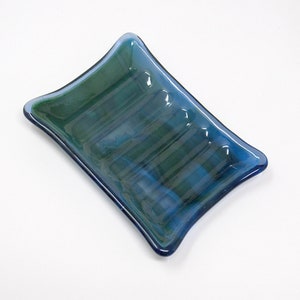 May include: A blue glass soap dish with a rippled texture. The dish is rectangular with rounded edges.